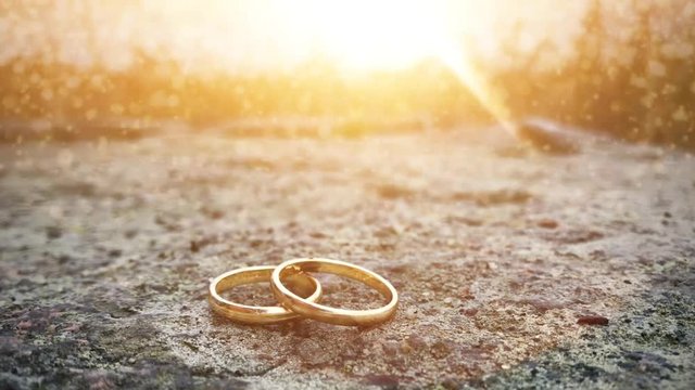 Two golden rings on stone with rays of sunlight cinema graphics motion endless loop.