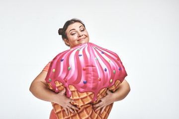 Brunette, chubby woman is holding a huge ice cream