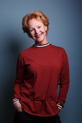 Mature woman with orange hair in front of a colored background