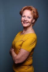 Mature woman with orange hair in front of a colored background