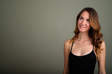 Young beautiful woman wearing sleeveless top against colored bac