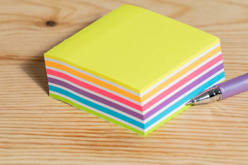 stack of sticky notes and ball pen on wooden table 