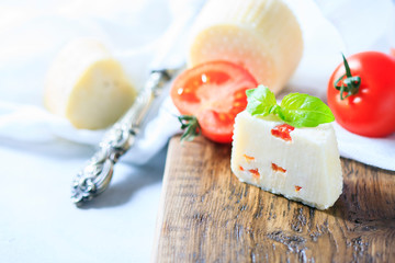 Homemade cheese with tomatoes on a light background. Copy space background.