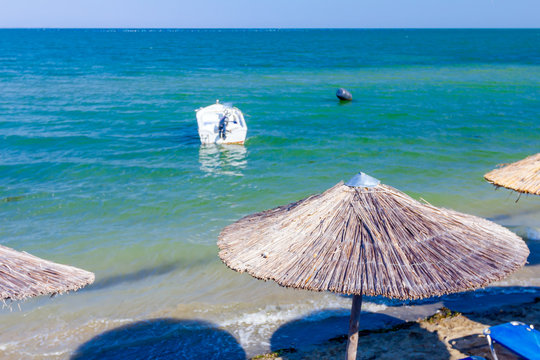 Umbrellas with loungers, chaise are placed next to the coastline, along water edge