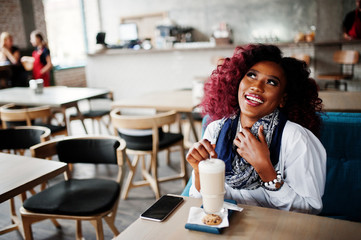 Attractive african american curly girl sitting at cafe with latte.
