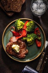 Grilled Beef steak with garlic butter and vegetables. Meat with grilled bell pepper, broccoli and onions.