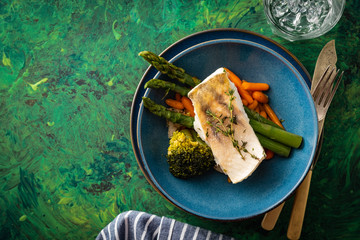 Pike perch fillet with asparagus, broccoli and carrots. Fried fish with stewed greens