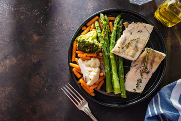Pike perch fillet with asparagus, broccoli and carrots. Fried fish with stewed greens