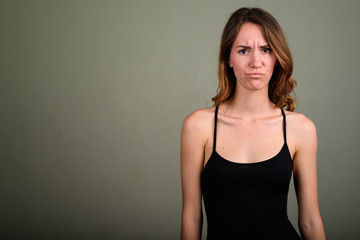 Young beautiful woman wearing sleeveless top against colored bac