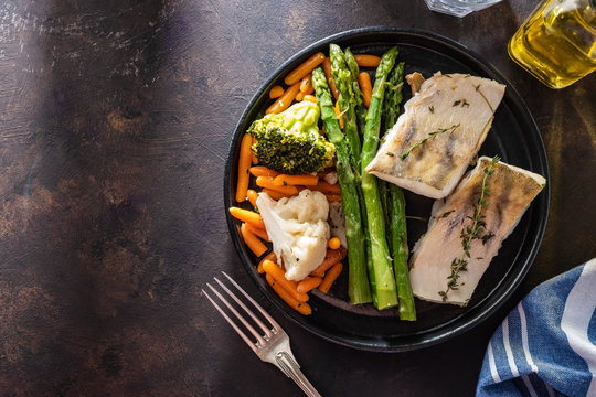 Pike perch fillet with asparagus, broccoli and carrots. Fried fish with stewed greens