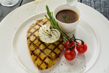 Grilled chicken with sauce and cherry tomatoes.