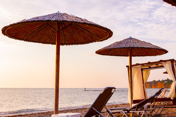 Morning light over umbrellas with loungers, chaise are placed next to the coastline, along water edge