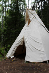 tall wigwam from dense beige fabric in the forest of Karelia