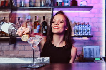 A beautiful girl bartender prepares an alcoholic cocktail with vodka