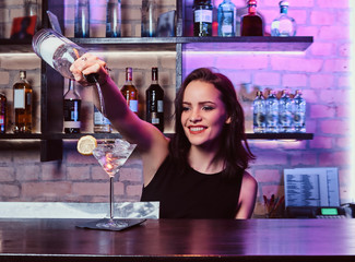 A beautiful girl bartender prepares an alcoholic cocktail with vodka