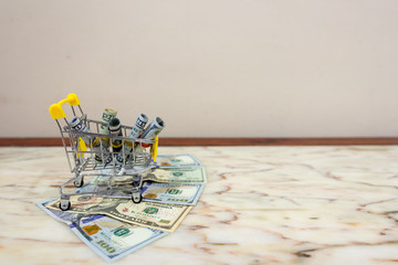 Business, finance and economy concept. Dollar and shopping cart on marble tile background with copy space. Selective focus.