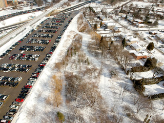 Parking lot filled with cars near commuter train transit at winter. Aerial view. The parking is jammed with cars in winter time. Citizens leaving there cars to travel on train to the city.
