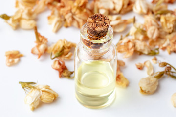 A bottle of jasmine essential oil with dried jasmine flowers