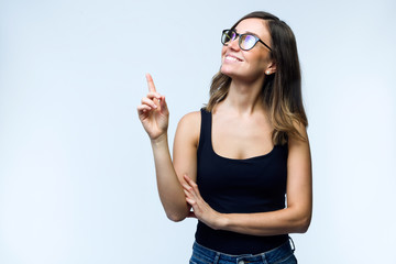 Beautiful young woman with eyeglasses showing and pointing over white background.