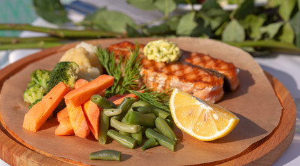 Vegetables and grilled meat on a wooden board