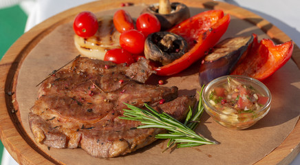 Vegetables and grilled meat on a wooden board