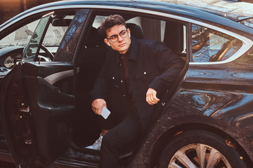 A stylish young man getting out of the luxury car.