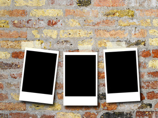 Three blank rectangular instant photo frames on multicolored brick wall background