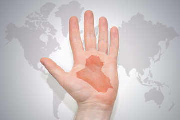 hand with map of iraq on the gray world map background.