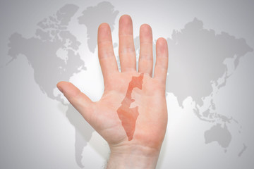 hand with map of israel on the gray world map background.