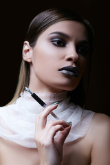 Obraz premium Portrait of a gorgeous dark-haired girl holding a syringe with poison. White translucent neck bandage.