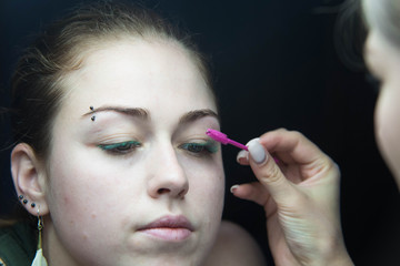 Obraz premium Eye lash extension procedure. Young beautiful woman eye with long false green eye lashes. Close up macro shot of fashion eyes in beauty salon.