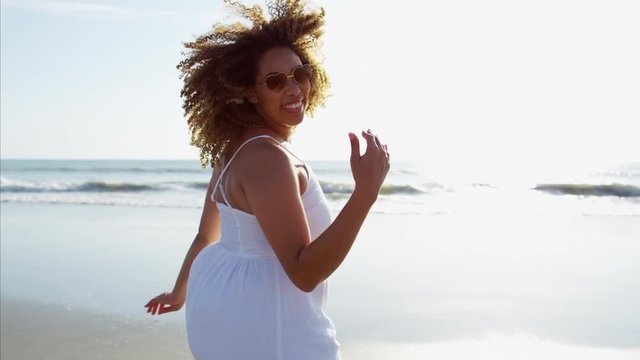 Portrait of plus size African American female enjoying vacation running through the waves by the ocean for leisure and health 