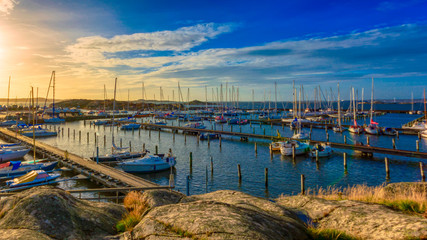 Obraz premium Bright sunny day at saltholmen gothenburg sweden with golden light spread over parked boats