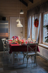 Table served for Christmas dinner, festive setting with decorations, burning candles and fir-tree branches