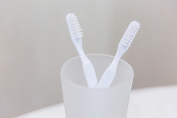 White toothbrushes in a glass in the bathroom. Two toothbrushes. Toothbrush
