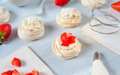 Strawberry pavlova cake nests, meringue decoration on a culinary table