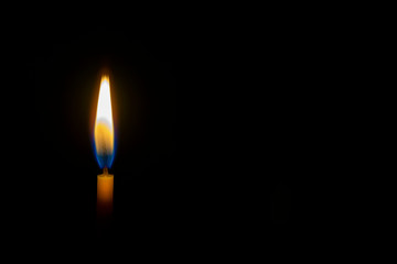 burning wax candle on a black background