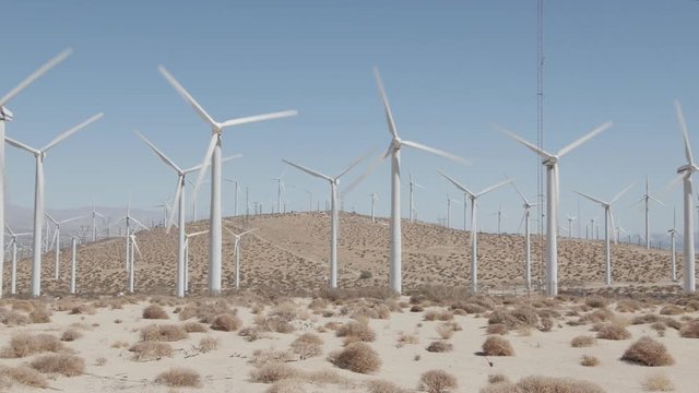 Wind farm desert landscape with wind turbines producing clean and renewable energy. Nature sourced electricity, sustainability concept. Filmed outside Palm Springs, California. Panning camera motion. 