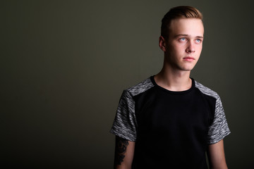 Young handsome man with blond hair against colored background