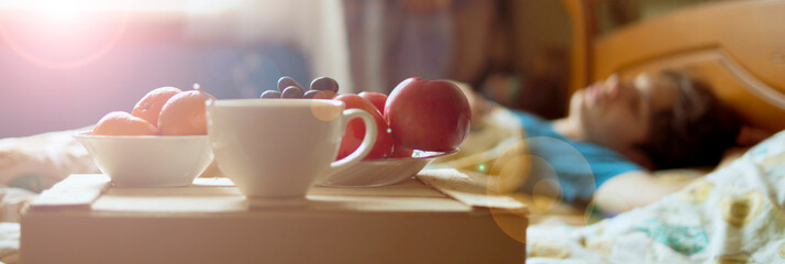 morning breakfast food on the wooden tray in the hotel bed next to the sleeping person f