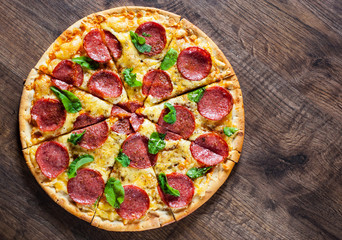 Pepperoni Pizza with Mozzarella cheese, salami, Tomato sauce, pepper, Spices and Fresh Basil. Italian pizza on wooden table background