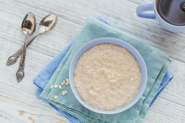 Oatmeal porridge bowl on the white wooden background. - obrazy, fototapety, plakaty