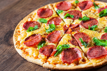 Pepperoni Pizza with Mozzarella cheese, salami, Tomato sauce, pepper, Spices and Fresh Basil. Italian pizza on wooden table background