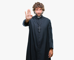 Handsome hispanic catholic priest man over isolated background doing stop sing with palm of the hand. Warning expression with negative and serious gesture on the face.