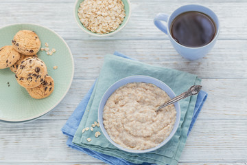 Oatmeal porridge bowl on the white wooden background.