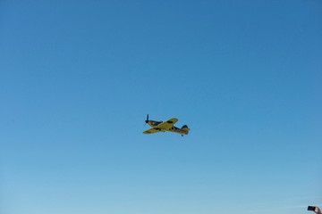 Fototapeta na wymiar Propellerflugzeug Oldtimer fliegt über den Himmel in der äußersten Ecke eine Hand mit Handy auf das Flugzeug gerichtet um zu fotografieren