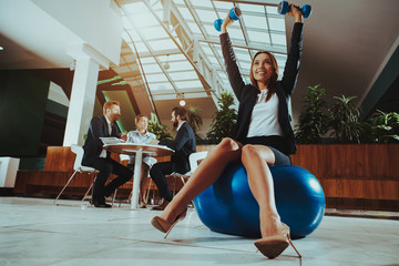 Woman Balance on Ball with Dumbbells in Office