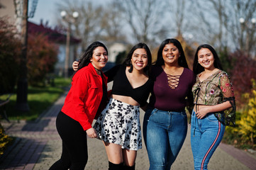 Group of four happy and pretty latino girls from Ecuador posed at street.