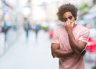 Afro american man wearing sunglasses over isolated background looking stressed and nervous with hands on mouth biting nails. Anxiety problem.