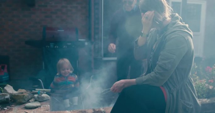 Young woman, toddler and senior man by the smoky barbecue
